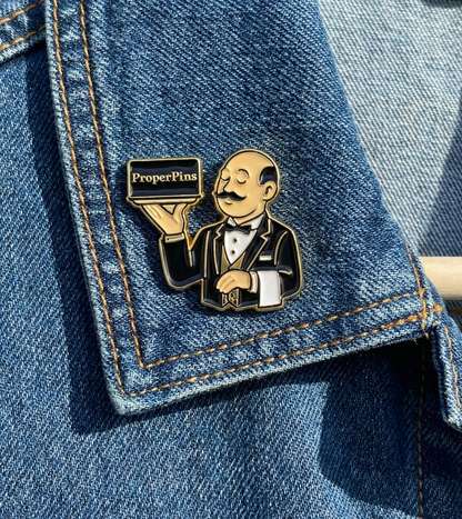 Custom soft enamel pin example - ProperPins butler mascot character holding a serving tray on denim jacket